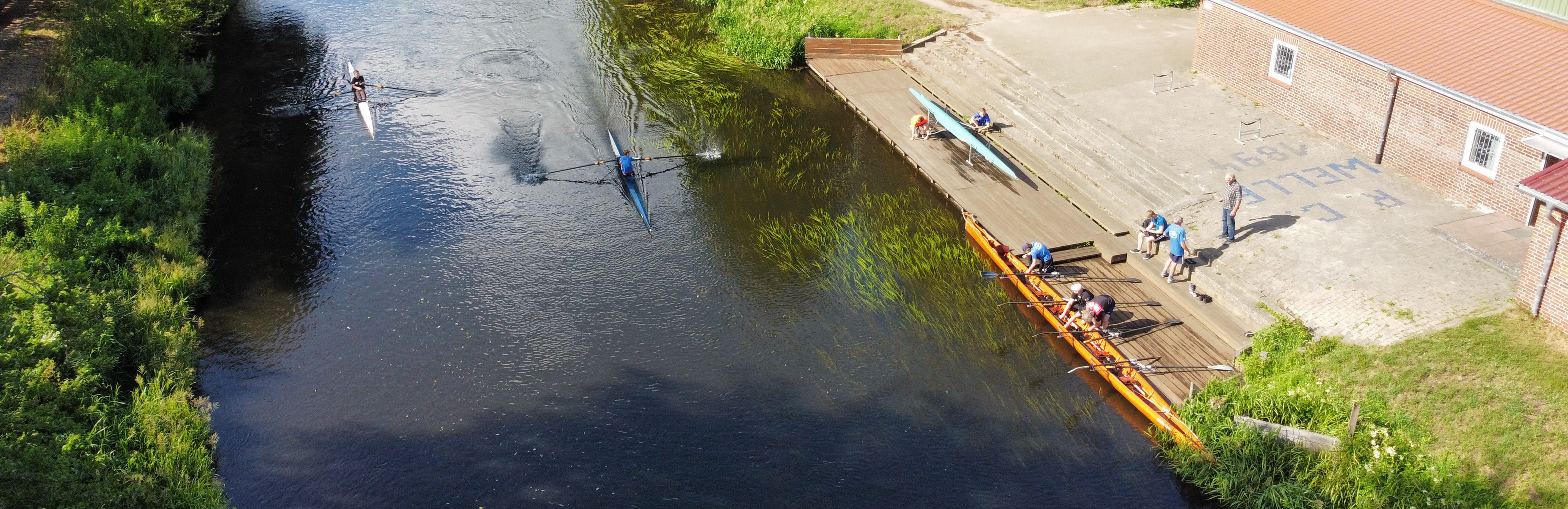 Menschen fahren in Booten auf einem Fluss, während eine Brücke die Szenerie überblickt.